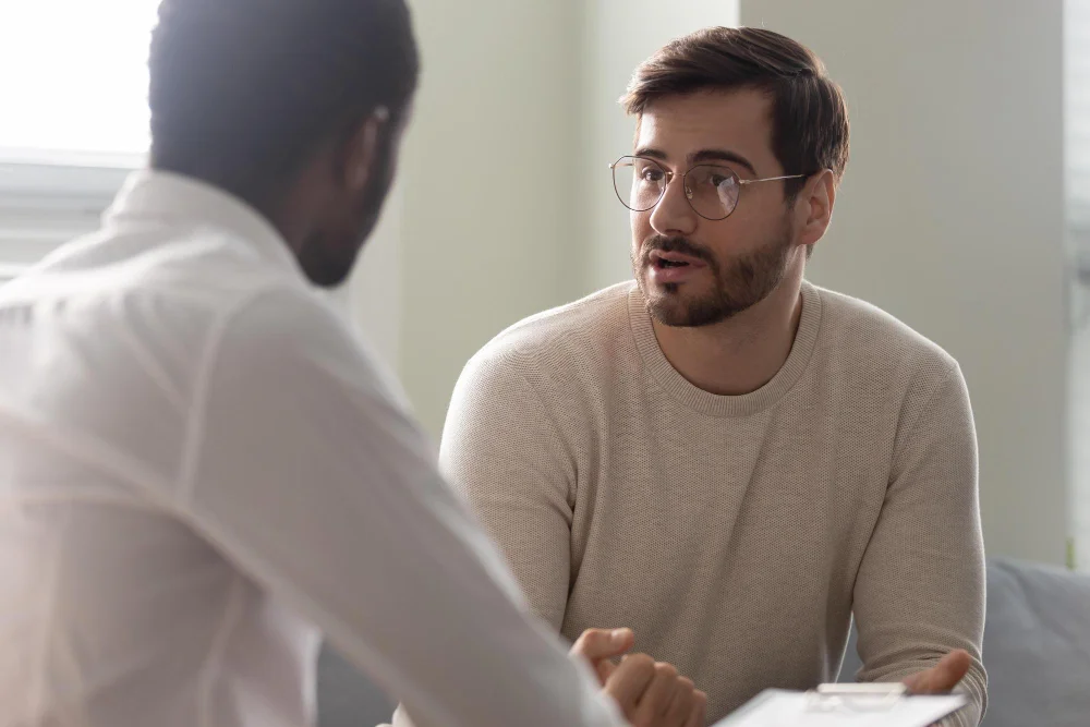 Man-Consulting-With-Practitioner-African-Psychologist-Holding-Clipboard-With-Card-Sitting-Front-Patient-Listens-His-Mental-Health-Complaints-Job-Interview-Process-Applicant-Hr-Manager Diversifying The Recruiting Process | Nw Recruiting Partners